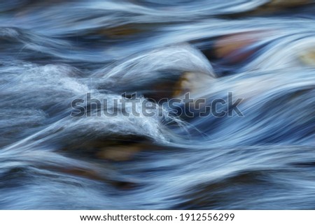 Closeup of Motion-Blurred Water Rapids Flowing over a Cobble Sto