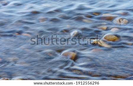 Closeup of Motion-Blurred Water Riffles  Flowing over a Cobble S
