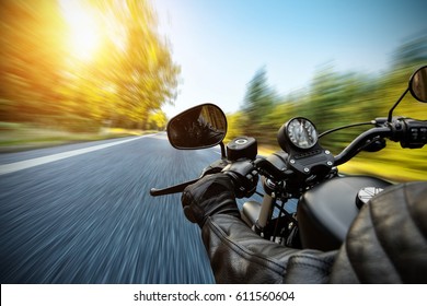 Close-up Of Motorbiker Riding On Empty Road In Forest With Sunrise Light, Concept Of Speed And Travel In Nature