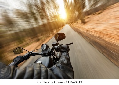 Close-up Of Motorbiker Riding On Empty Road In Forest With Sunrise Light, Concept Of Speed And Travel In Nature