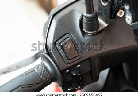 Close-up of a motorcycle handlebar switch for high and low beam headlights, highlighting buttons and functionality