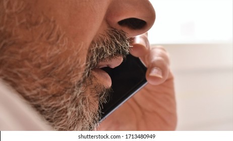 Close-up Of The Mouth Of A Bearded Man Talking On A Smarphone. Communication Technology Concept.