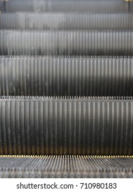 Close-up of a moving down staircase. Escalator in a shopping centre as a background. An electric escalator with yellow bands.