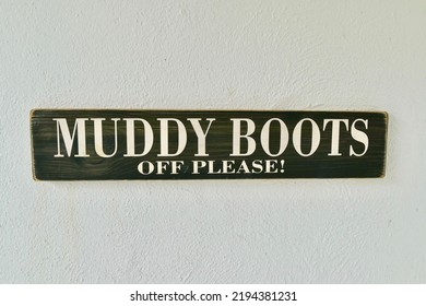 A Closeup Of A Muddy Boots Off Please Sign On A White Wall