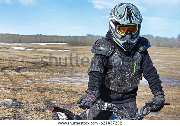 Closeup of a\
muddy boy in bike protection\
gear.