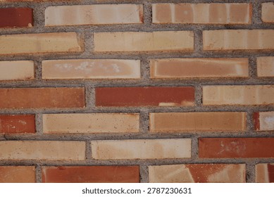 Close-up of a multicolored brick wall with horizontal masonry pattern and textured surface in an urban architectural setting