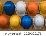 Close-up, multi-colored construction helmets for engineering and worker construction site hanging on an old wooden wall