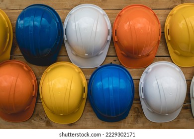 Close-up, multi-colored construction helmets for engineering and worker construction site hanging on an old wooden wall