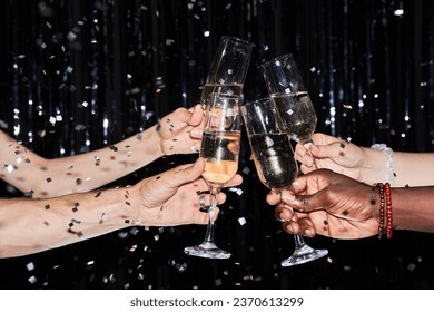 Closeup of multiethnic group of friends toasting with champagne glasses at party against glittering background with confetti - Powered by Shutterstock