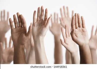 Closeup of multiethnic men and women raising hands against white background - Shutterstock ID 144918361