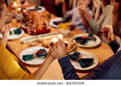 Close-up of multigeneration family blessing the food while saying grace during Thanksgiving dinner at dining table.