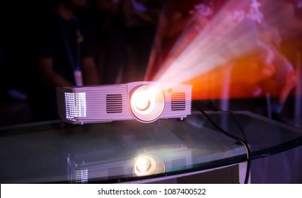 Close-up multimedia projector with blurred people background.