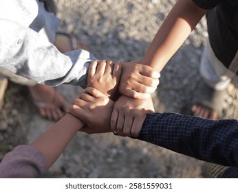 Close-up of multiple hands gripping each other's wrists in a strong, united circle, symbolizing teamwork, unity, friendship, and support. The image captures a diverse group of people standing together