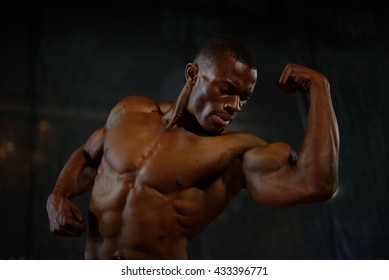 Close-up Muscles Of African American Handsome Body Builder Posing With Naked Torso On The Black Studio Background