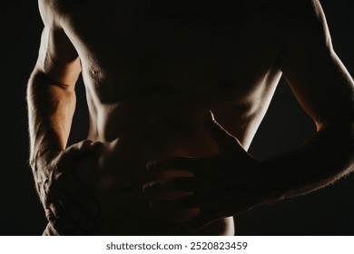 Close-up of a muscular male torso in dramatic lighting showcasing strength, fitness, and bodybuilding. - Powered by Shutterstock