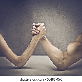 Closeup of a muscular man playing arm wrestling with a skinny one