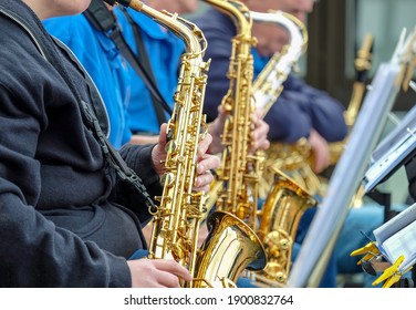 Close-up of musicians play saxophone in a big band at a public event open air, selective focus 