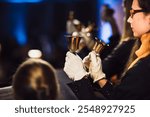 Close-up of musicians playing handbells during a formal concert, wearing white gloves for precision. Elegant brass bells shine under warm lights, creating a festive and harmonious atmosphere