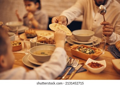 Close-up of Muslim father passing his son Lafah Bread during dinner at dining table on Ramadan. - Shutterstock ID 2131452715