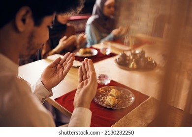 Close-up of Muslim man praying while eating with his family during Ramadan at home. 