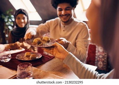 Close-up of Muslim people eating baklava for dessert at home.