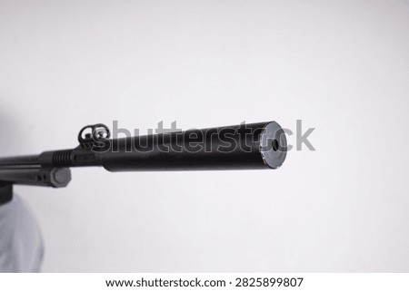 Closeup of Muzzle Opening and Attached Silencer on Modern Airgun Barrel Against White Background