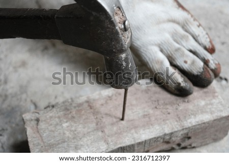 Closeup of nailing into a wooden board.Carpenter hands using hammer hit the nail on wood.