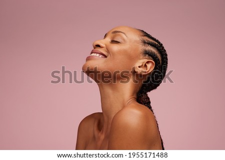 Close-up of a natural beauty smiling on pink background. Woman with beautiful skin having braided hair smiling and eyes closed.