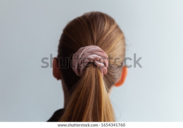 Close-up of a natural blonde hair,\
tied up in a ponytail by pink velvet scrunchie, back view\
