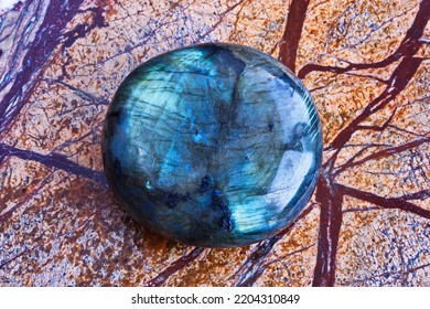 Close-up of natural gemstone polished blue-green labradorite mineral on brown polished marble slab. - Shutterstock ID 2204310849