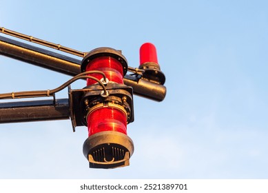 Close-up of navigation lights on a large cargo ship, the lamps standing out sharply against the clear blue sky. The detail captures the essential maritime equipment.
