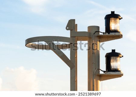 Close-up of navigation lights on a large cargo ship, the lamps standing out sharply against the clear blue sky. The detail captures the essential maritime equipment.