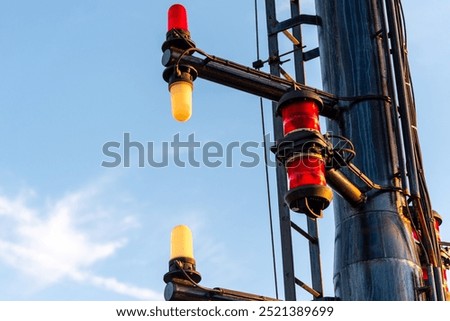 Close-up of navigation lights on a large cargo ship, the lamps standing out sharply against the clear blue sky. The detail captures the essential maritime equipment.
