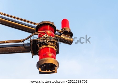 Close-up of navigation lights on a large cargo ship, the lamps standing out sharply against the clear blue sky. The detail captures the essential maritime equipment.
