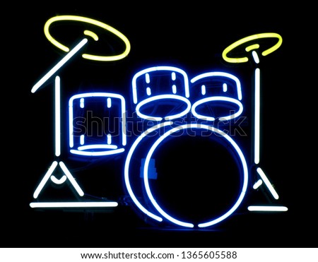 A closeup of a neon drum set sign on display in a business window