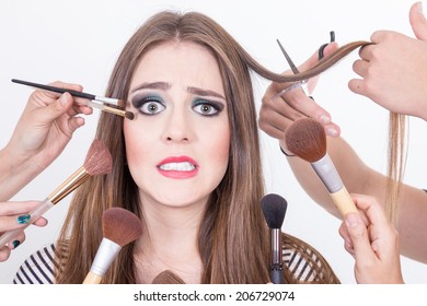 Closeup Of Nervous Beautiful Blond Girl Getting Hair And Makeup Done Isolated Over White