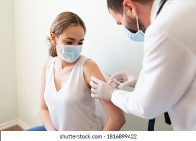 Closeup Of A Nervous Woman And Her Doctor Wearing Face Masks And Getting A Vaccine Shot In A Doctor's Office