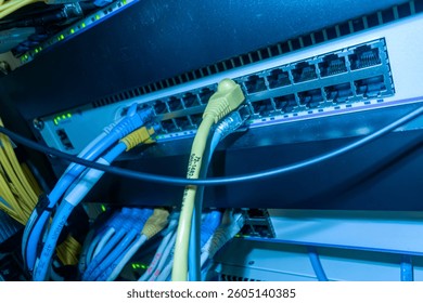 Close-up of network cables connected to a server rack with glowing LED lights. The image showcases modern networking equipment in a technology environment.