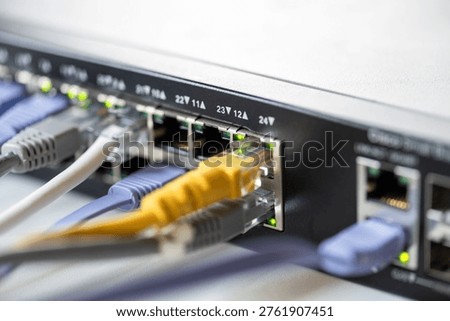 Close-up of a network switch with multiple colored Ethernet cables connected, indicating active data transfer with glowing LED indicators.