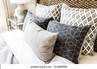Closeup of new bed comforter with decorative pillows, headboard in bedroom in staging model home, house or apartment