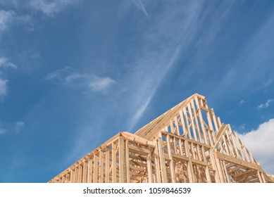 Close-up New Build Roof With Wooden Truss, Post And Beam Framework. Gables Roof On Stick Built Home Under Construction And Cloud Blue Sky. Timber Frame House In South Irving, Texas, USA