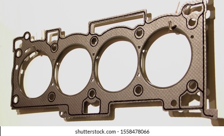 Closeup new engine cylinder head gasket with metal rings and sealing stripe, four cylinder car motor repair parts