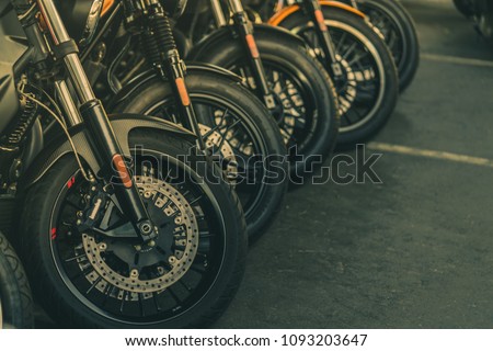 Closeup of new motorbike front wheel . Big bike parked on asphalt road. Iconic motorcycle with sports design. Black tire with unique pattern and spoked wheels.