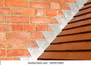 Closeup Of New Plain Red Clay Tiles And Lead Flashing On A Pitched Roof In The UK