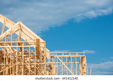 Close-up new stick built home under construction under blue sky in Humble, Texas, US. Framing structure/wood frame of wooden houses/home. House construction and real estate concept background.