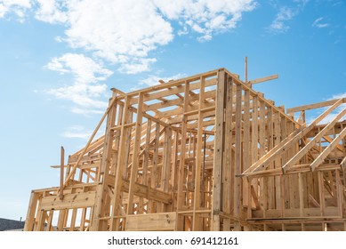Close-up new stick built home under construction under blue sky in Humble, Texas, US. Framing structure/wood frame of wooden houses/home. House construction and real estate concept background.