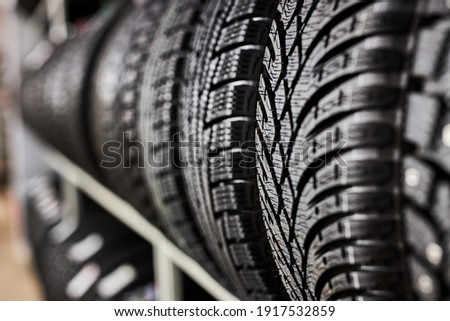 close-up new tires in the auto repair service center, brand new winter tires with a modern tread isolated. selective focus. tire stack background.winter season, no people