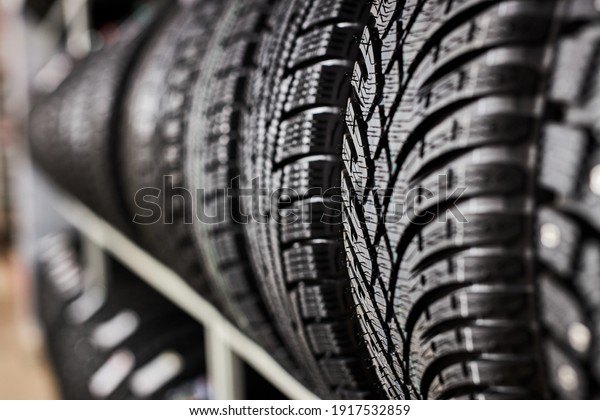 close-up new tires in\
the auto repair service center, brand new winter tires with a\
modern tread isolated. selective focus. tire stack\
background.winter season, no\
people