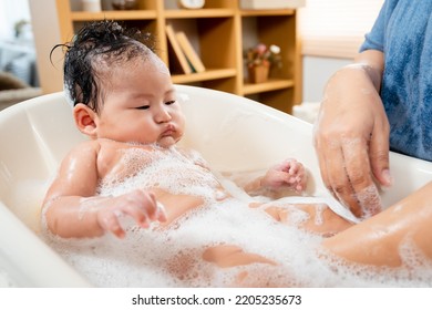 Close-up Of A Newborn Asian Baby Lying In The Tub A Single Mother Gently Bathes Her Newborn Daughter, And Her Daughter's Face And Body Are Filled With Bubbles.