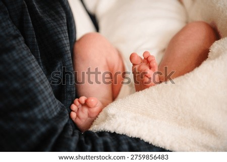 Close-up of a newborn baby's delicate feet wrapped in a soft white blanket during a baptism ceremony. A tender moment capturing innocence and the beginning of a spiritual journey.